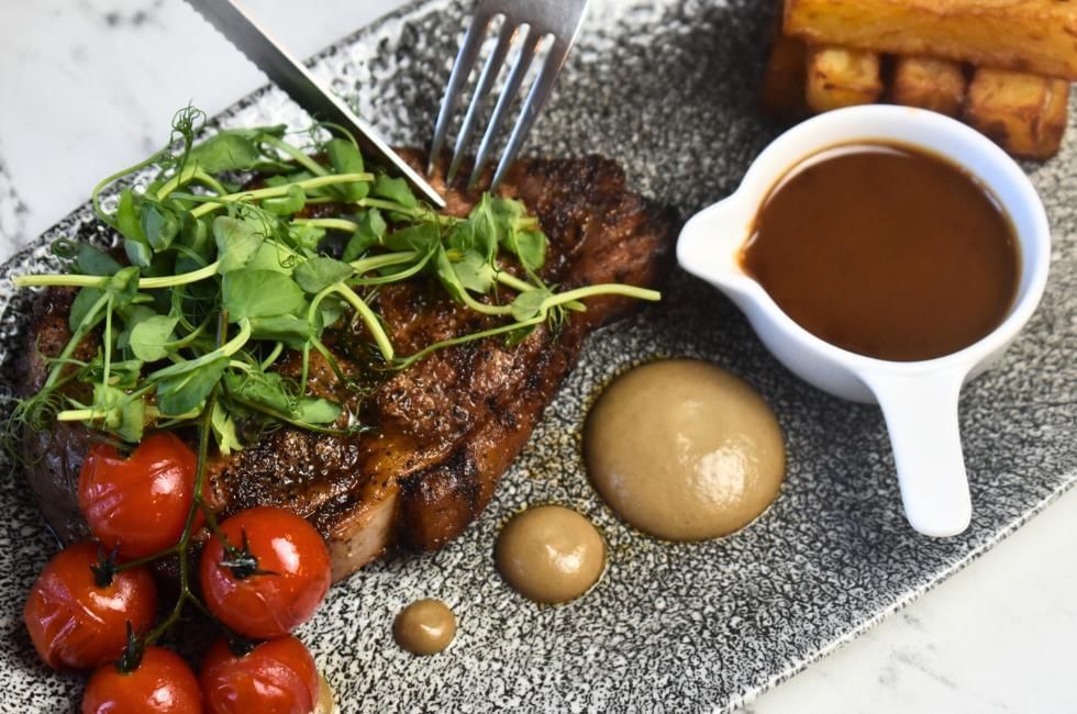 cutting into steak with peppercorn sauce at easthampstead park in wokingham