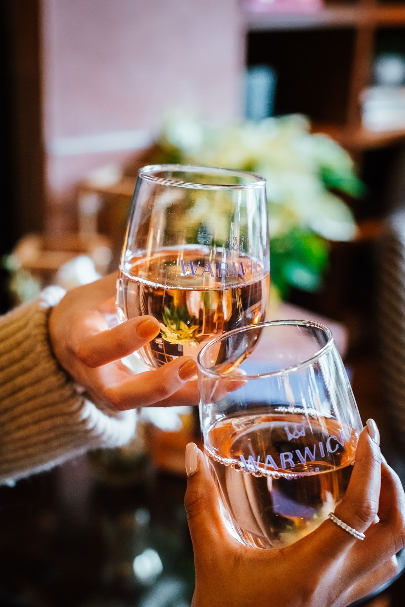Two guests clinking wine glasses by a blurred floral arrangement at Warwick Denver