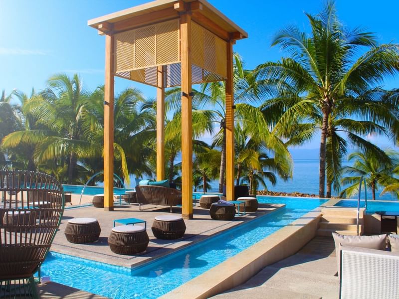 Poolside with cabana and palm trees overlooking the ocean at Fiesta Americana