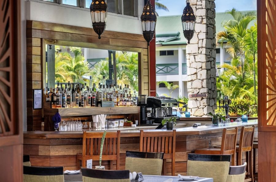 Indoor bar with wooden counter, stools, and tropical decor at Tokatoka Resort in Fiji.