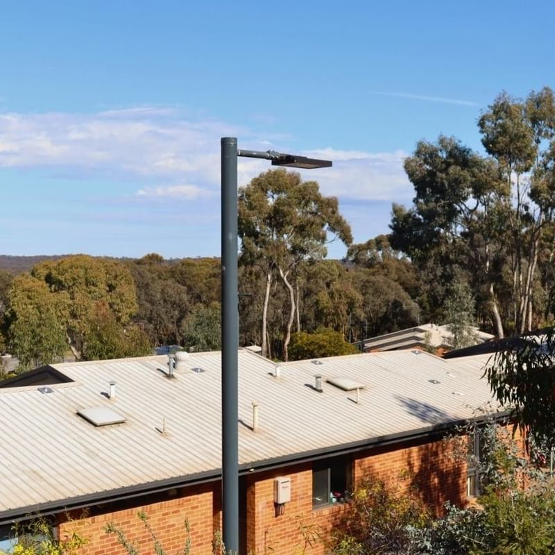 Tall lamp post in front of La Trobe University Terraces building with blue sky in background.