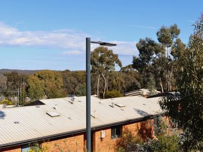 Tall lamp post in front of La Trobe University Terraces building with blue sky in background.