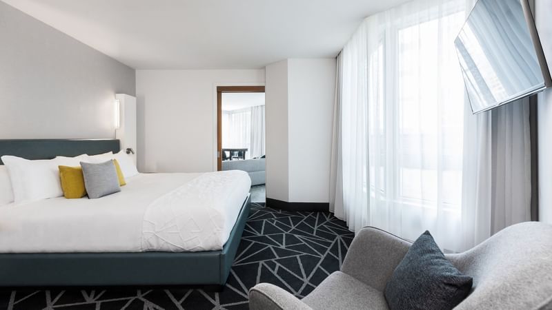 Large bed, armchair with large windows in Penthouse Suite Sainte-Catherine at Warwick Le Crystal