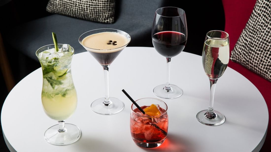 Selection of stylish cocktails, red wine, and champagne on a table in Level One Bar at Ibis Adelaide