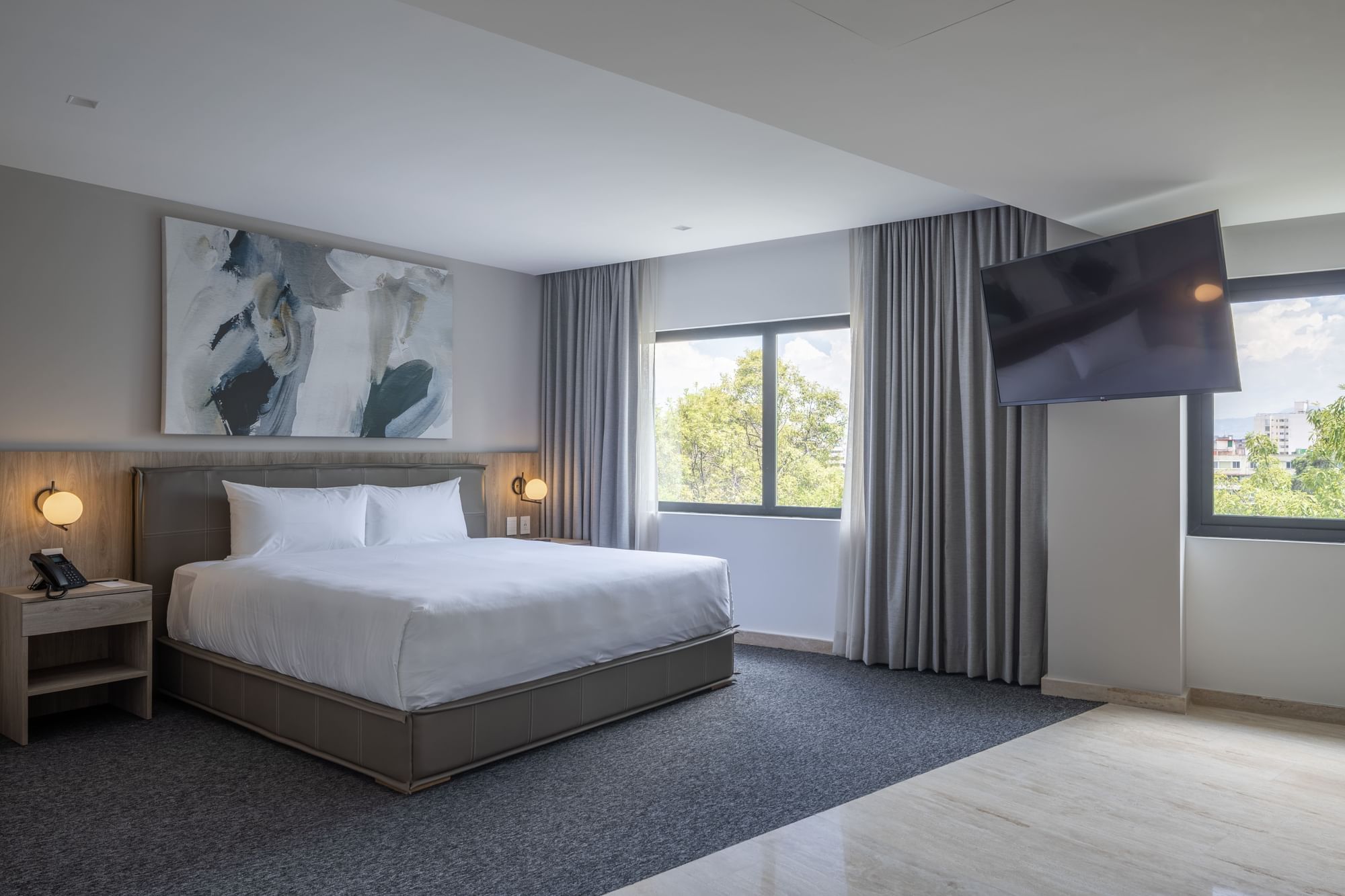 Modern hotel room with large bed, flat screen TV, and scenic window view at Elements by Marquis