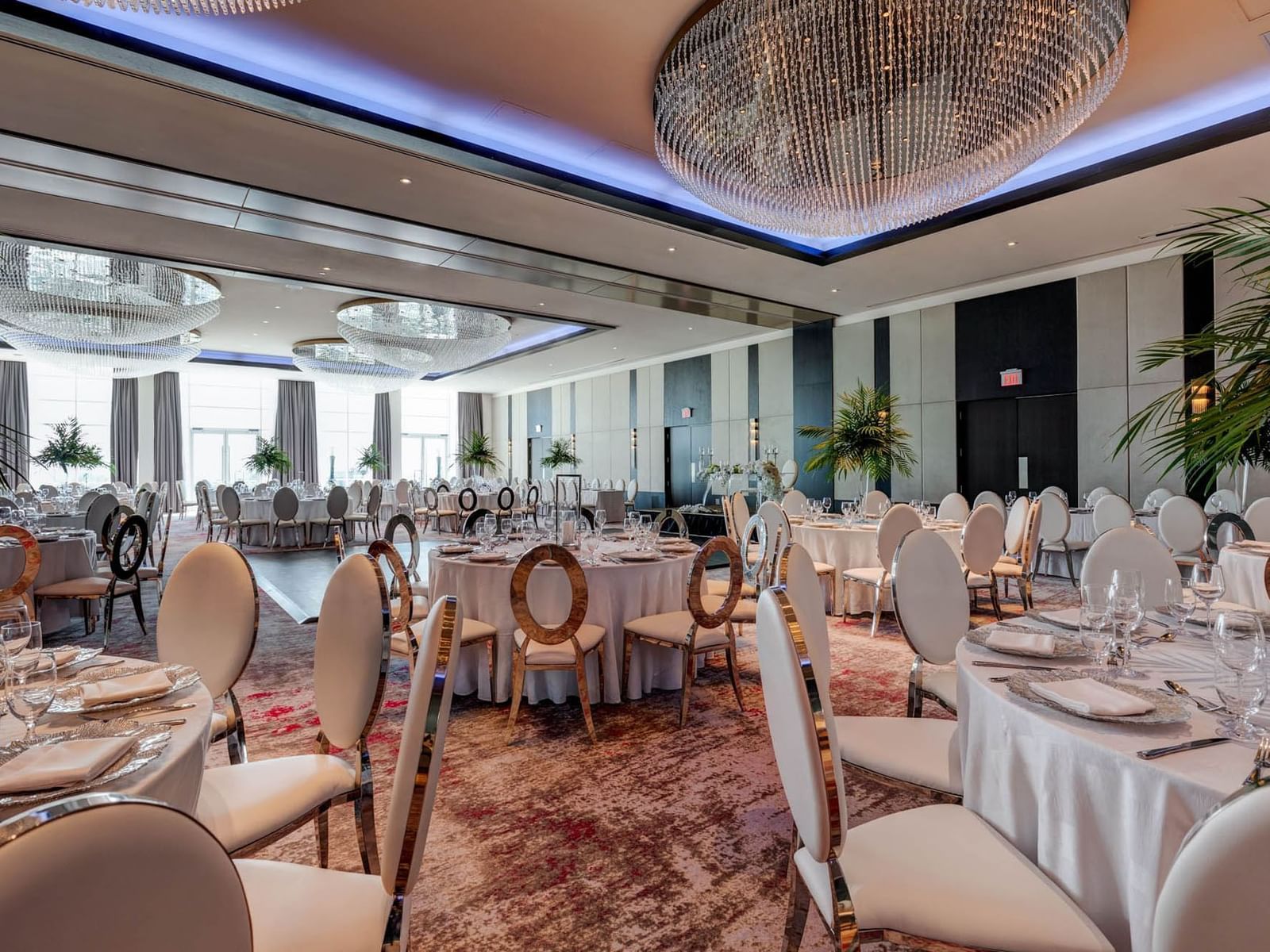 Victory Ballroom with round tables set for dining, large chandeliers above at Hotel X Toronto