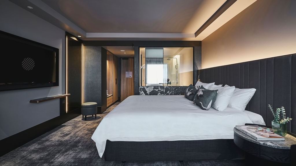 Modern Deluxe Executive Room with king bed, dark upholstered headboard, and ambient lighting at Pullman East Melbourne.