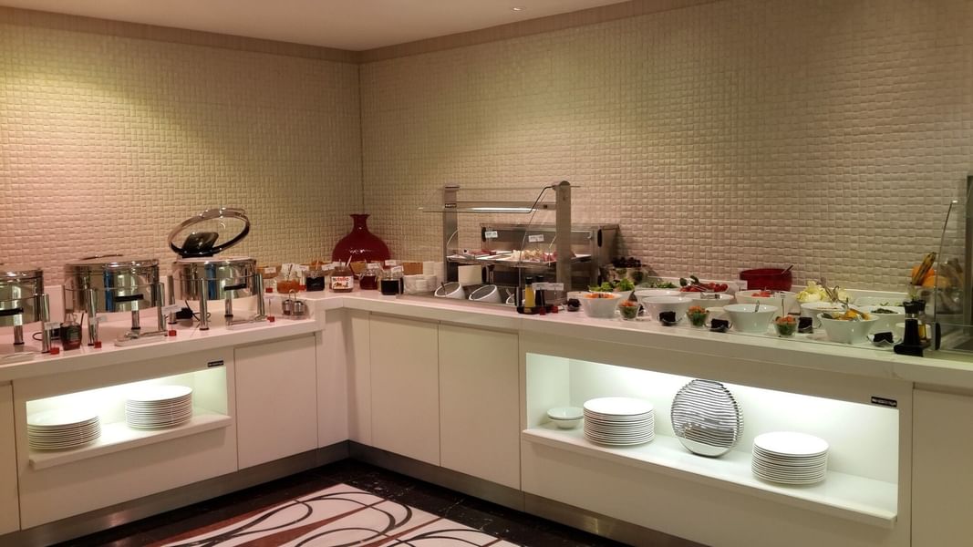 Breakfast buffet by a white counter surrounding fresh fruit and salad bowls in Breakfast & In-Room Dining at Warwick Ankara
