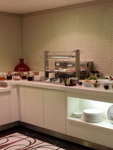 Breakfast buffet by a white counter surrounding fresh fruit and salad bowls in Breakfast & In-Room Dining at Warwick Ankara