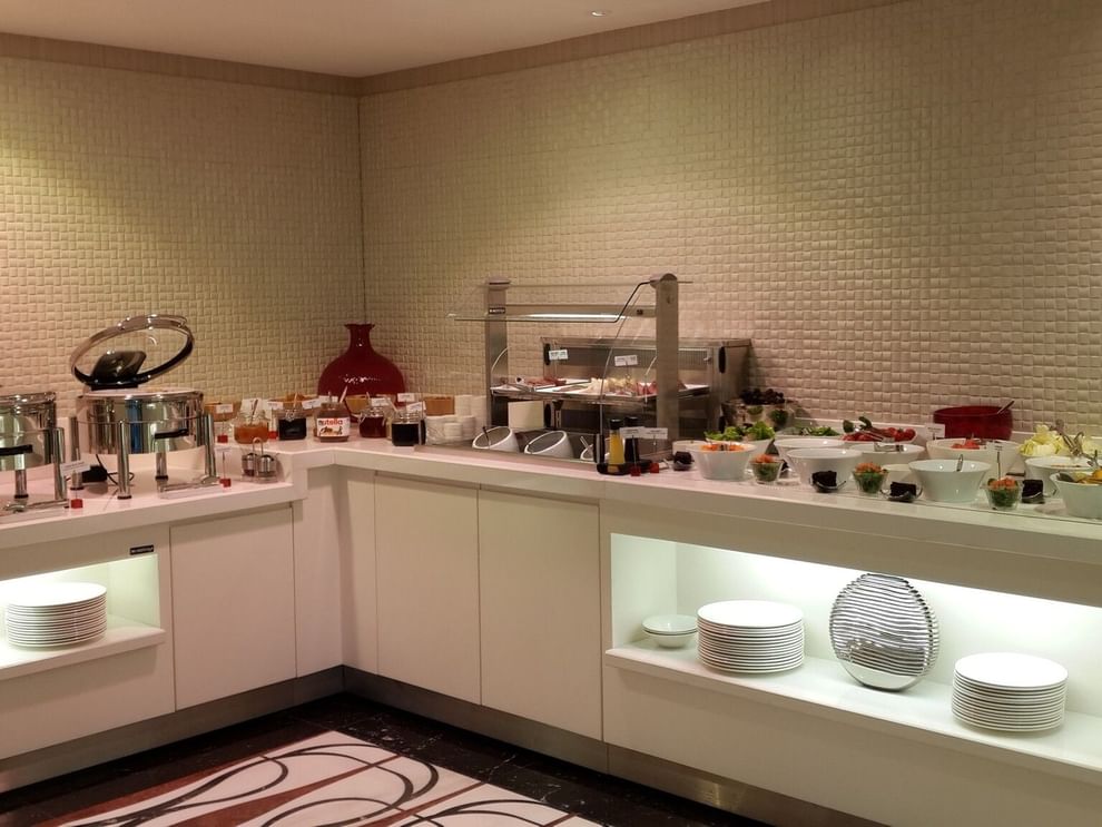 Breakfast buffet by a white counter surrounding fresh fruit and salad bowls in Breakfast & In-Room Dining at Warwick Ankara