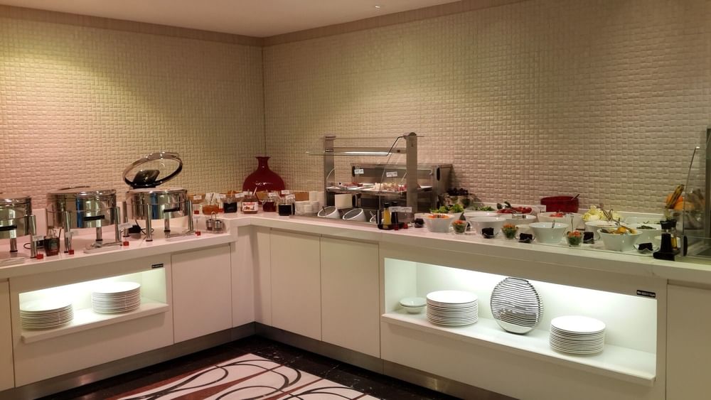 Breakfast buffet by a white counter surrounding fresh fruit and salad bowls in Breakfast & In-Room Dining at Warwick Ankara