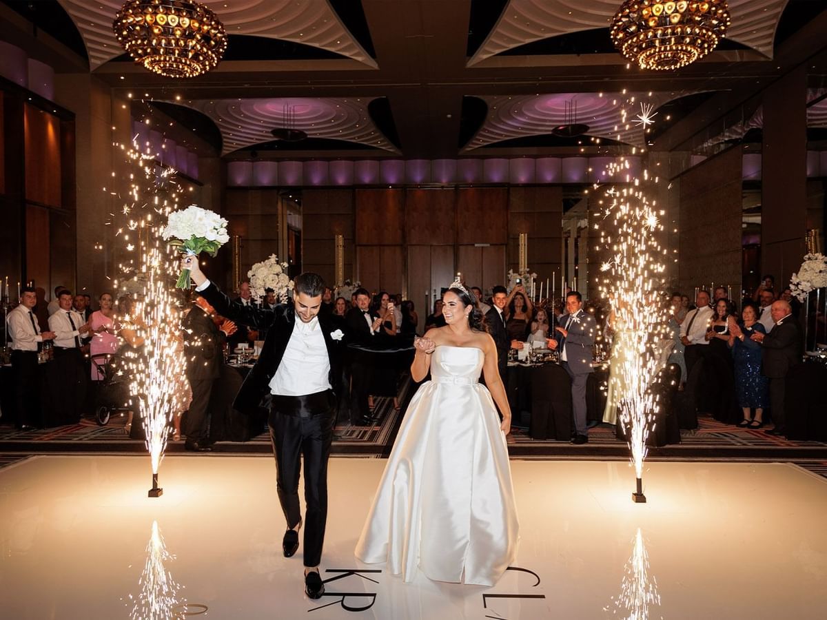 Clarissa and Kristian walking hand in hand with sparkler fountains on a dance floor at Crown Towers Perth