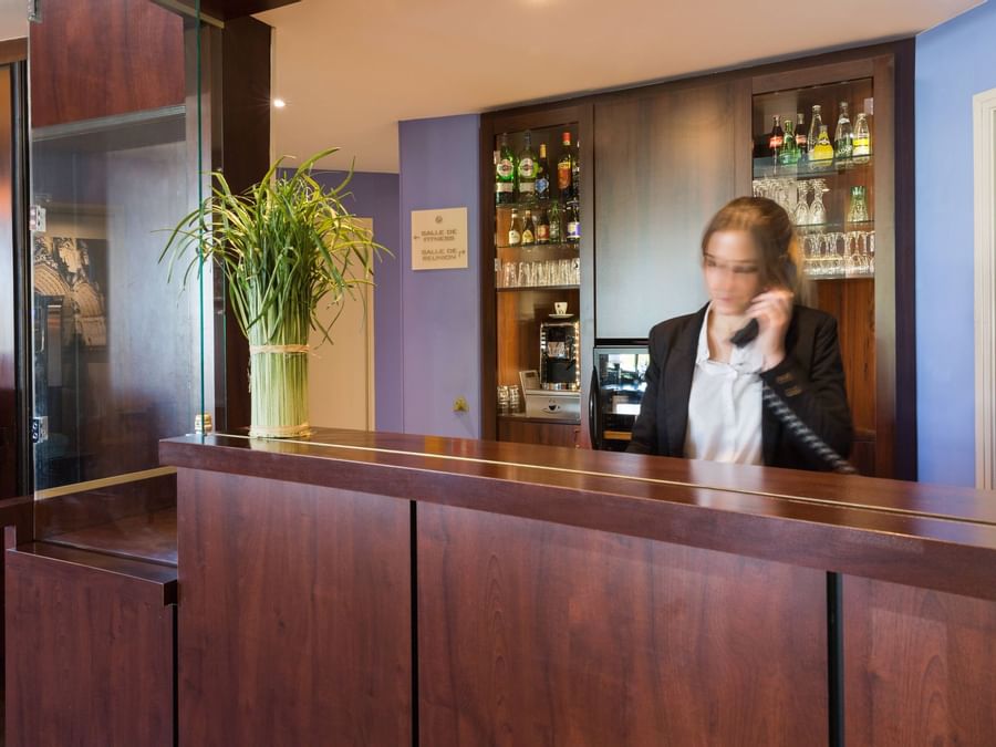 A receptionist at the reception desk in Hotel Quayls Reims
