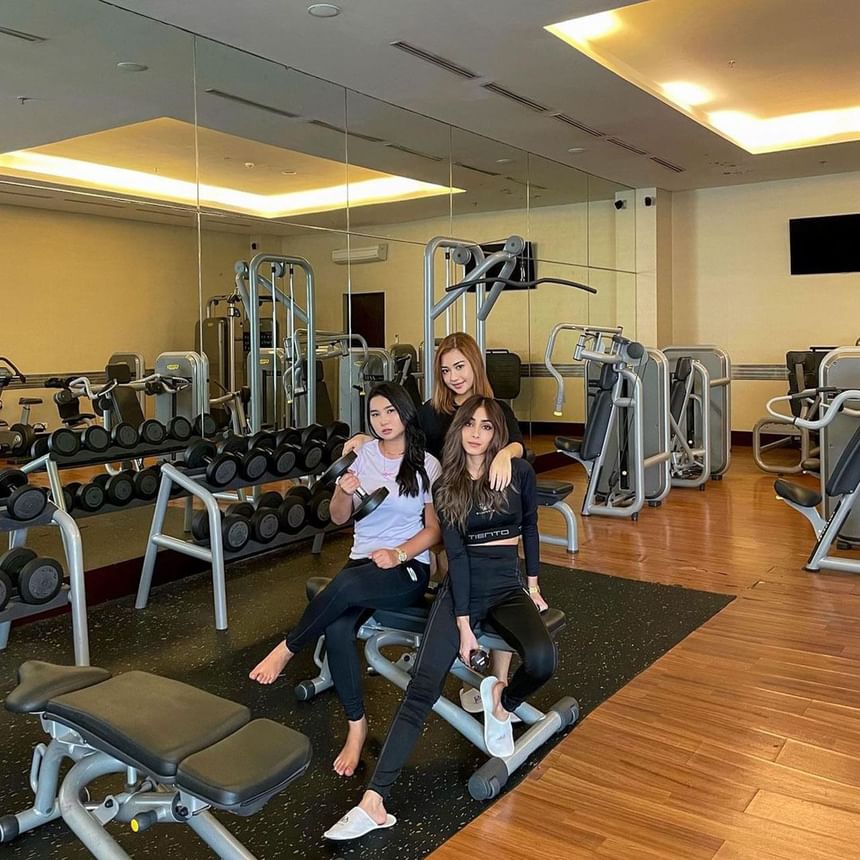 Three ladies posing in a fully equipped gym at Po Hotel Semarang