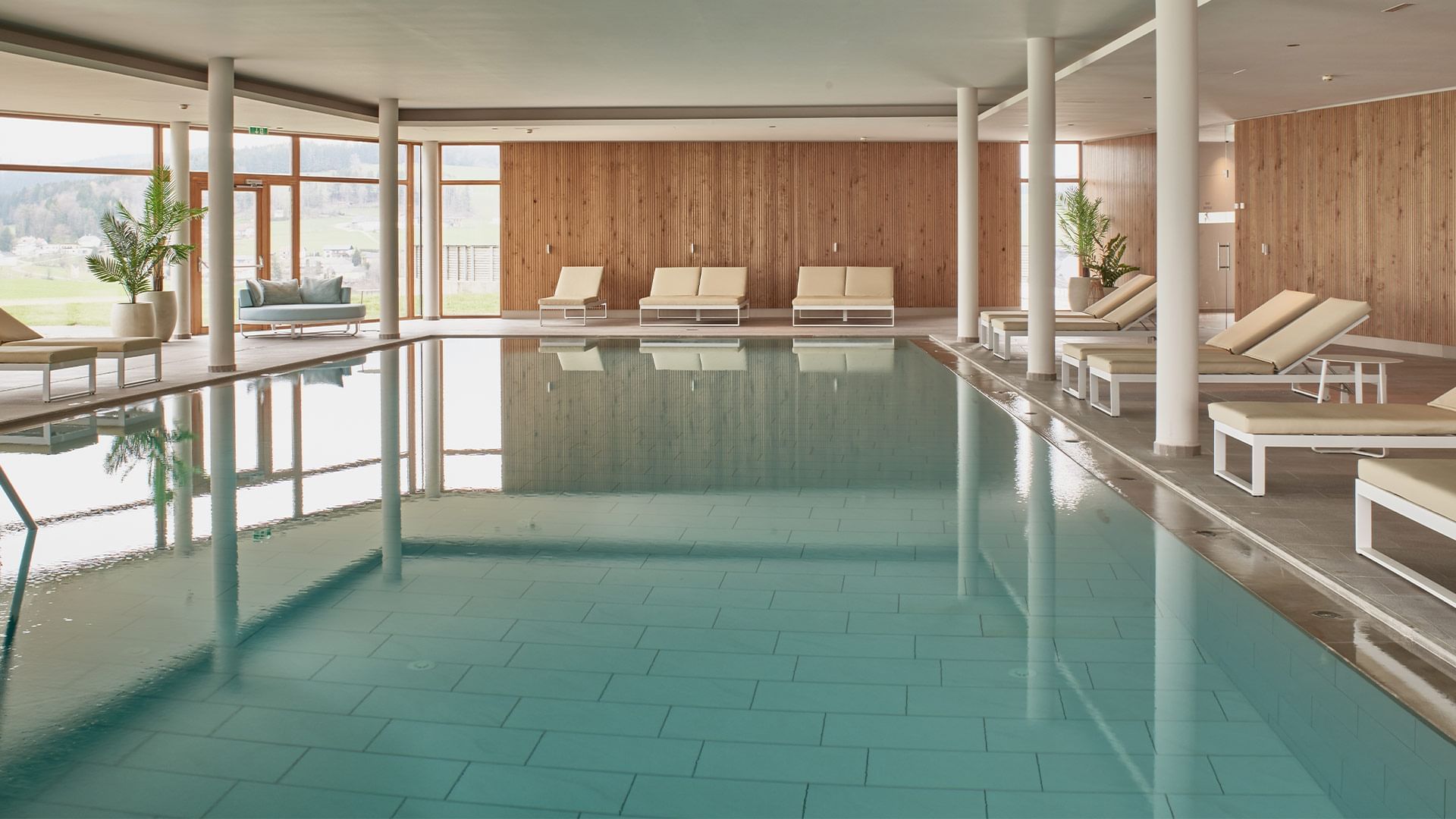 Indoor pool area with loungers at Falkensteiner Genuss & Wohlfühlhotel Mühlviertel