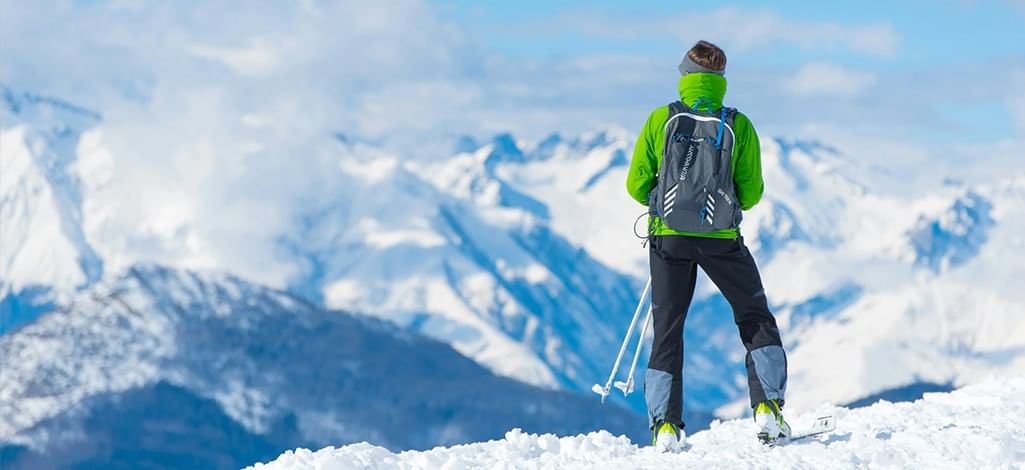 A person stands at the top of a ski hill, admiring the view of the Rocky Mountains.