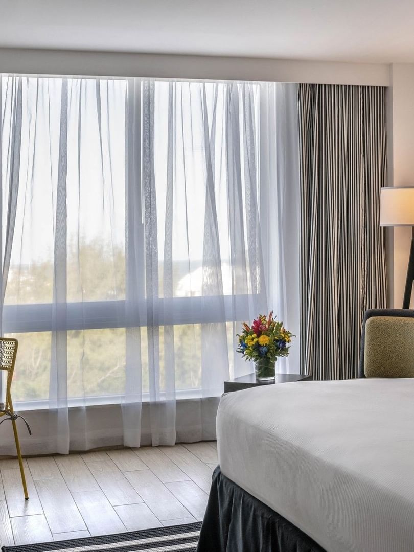 Island View with White bed by a yellow chair under a black floor lamp at Warwick Paradise Island Bahamas