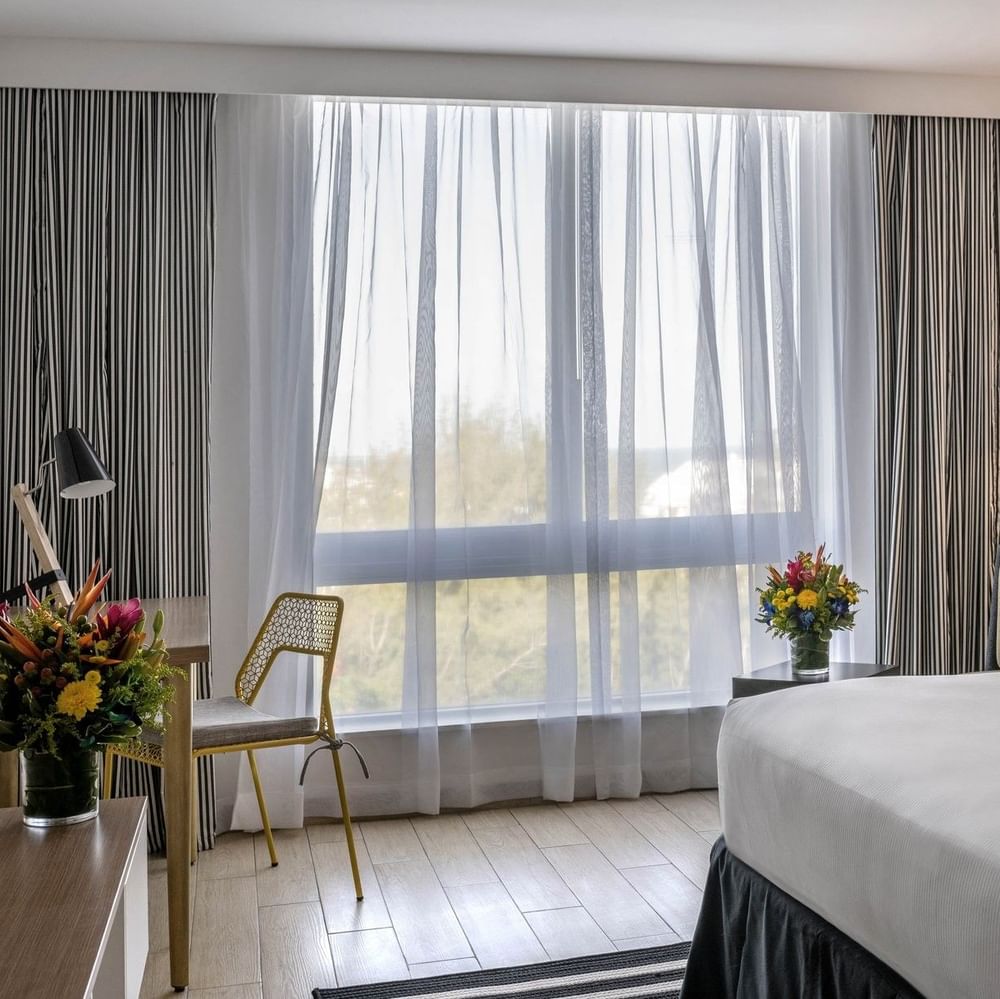 Island View with White bed by a yellow chair under a black floor lamp at Warwick Paradise Island Bahamas