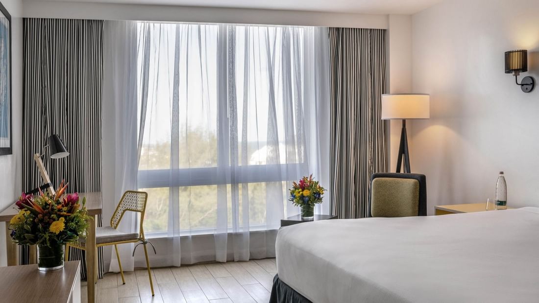 Island View with White bed by a yellow chair under a black floor lamp at Warwick Paradise Island Bahamas