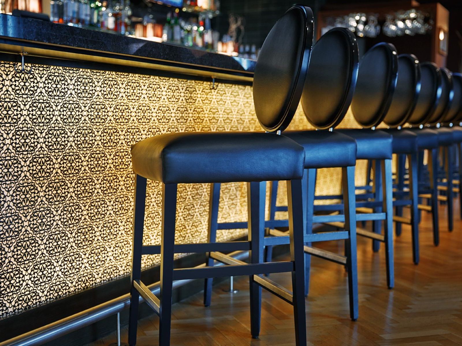 Row of stylish bar stools facing illuminated counter at Hotel Arista, Naperville.