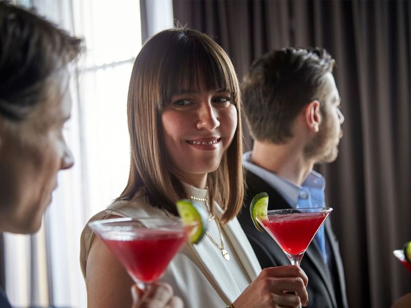 Two people holding a cocktail glass in a gathering at Fiesta Americana