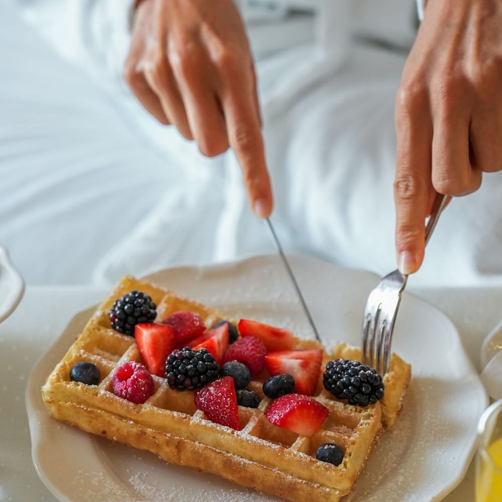 Waffle with fresh mixed berries and powdered sugar served in-room by a guest at Warwick Grand Place Brussels