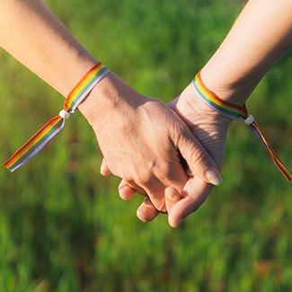 hand holding wearing pride bracelets