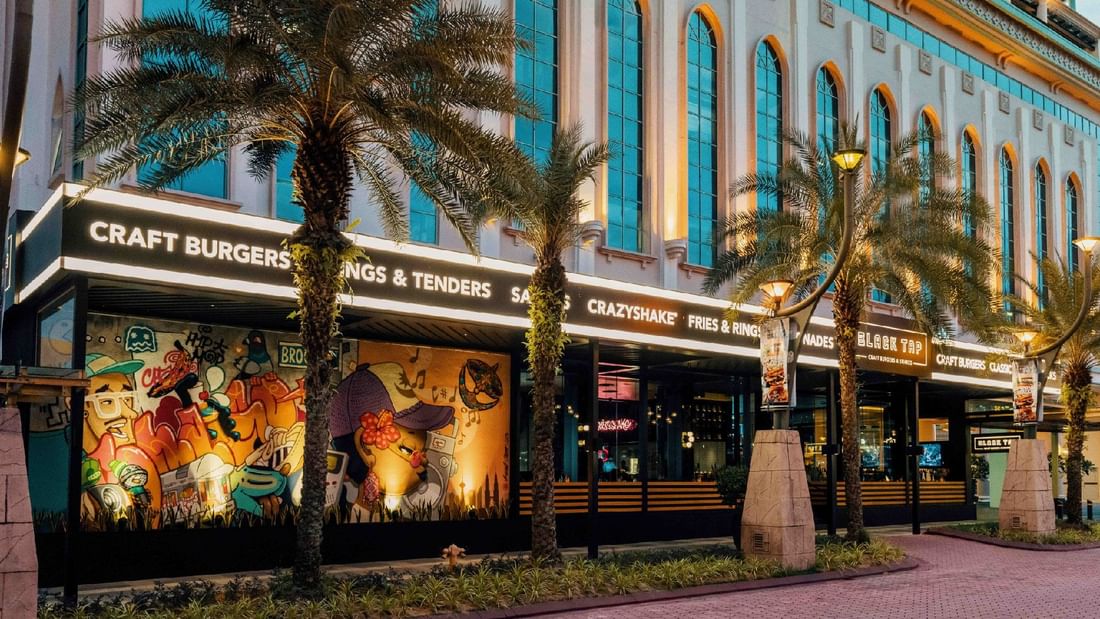 Exterior of a restaurant near Sunway Hotel Pyramid, featuring bold graffiti and promoting a happy hour offer