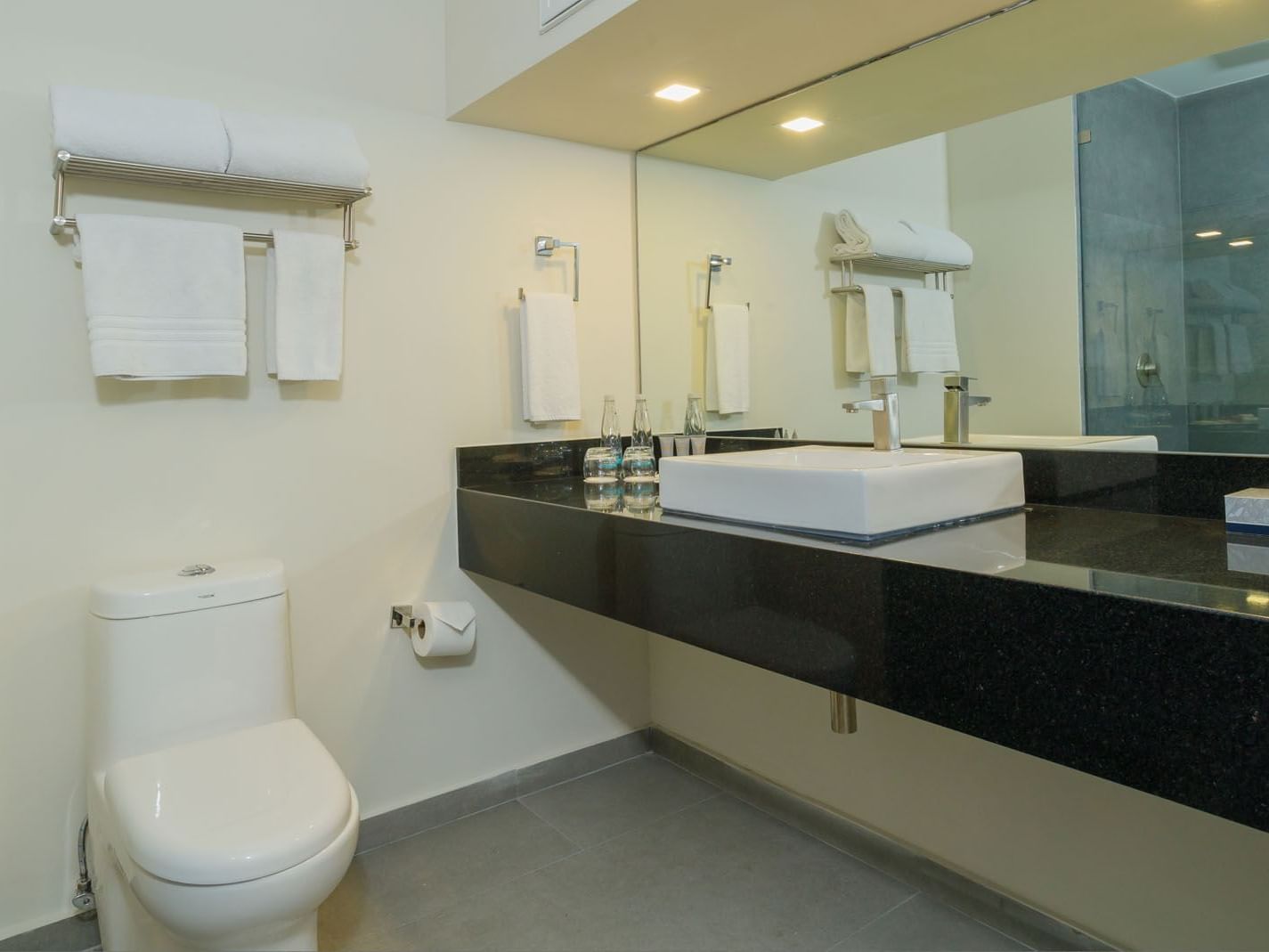 King Master Suite bathroom with a black granite vanity, square vessel sink, and fresh towels at Real Inn Mexicali