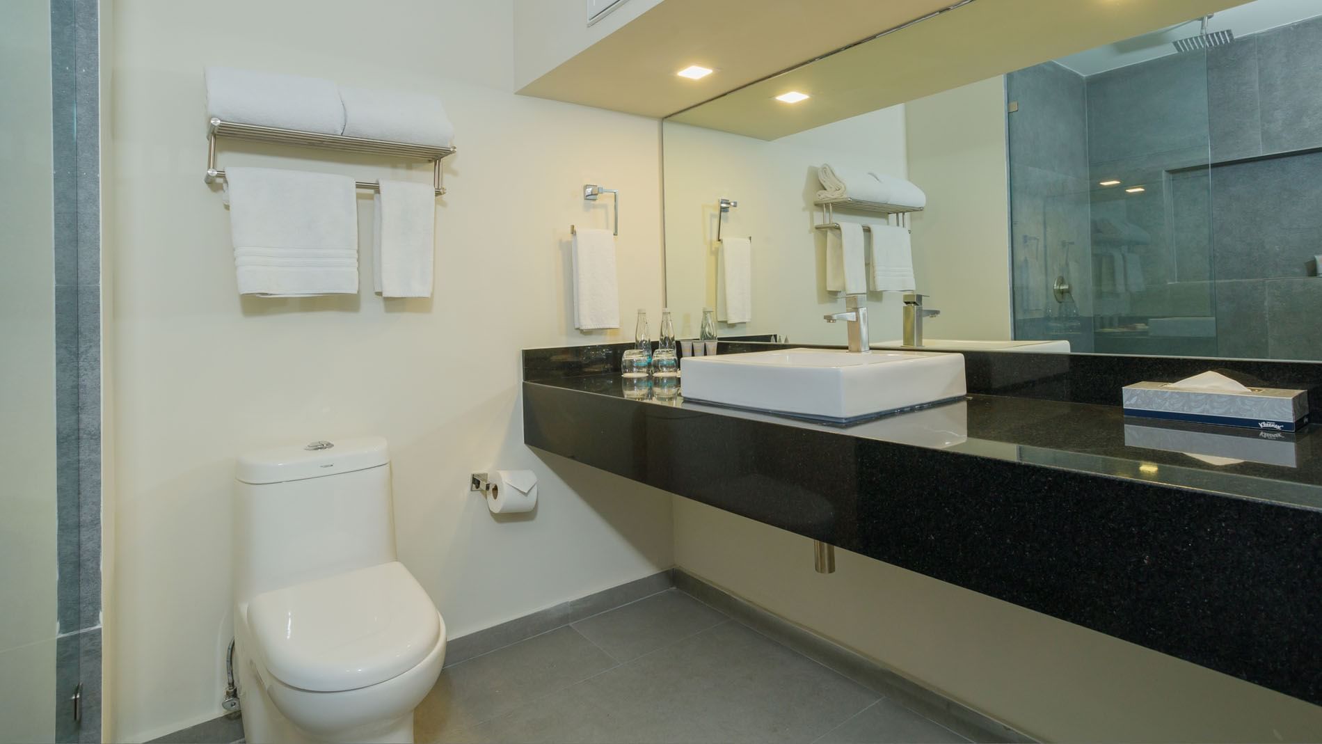 King Master Suite bathroom with a black granite vanity, square vessel sink, and fresh towels at Real Inn Mexicali