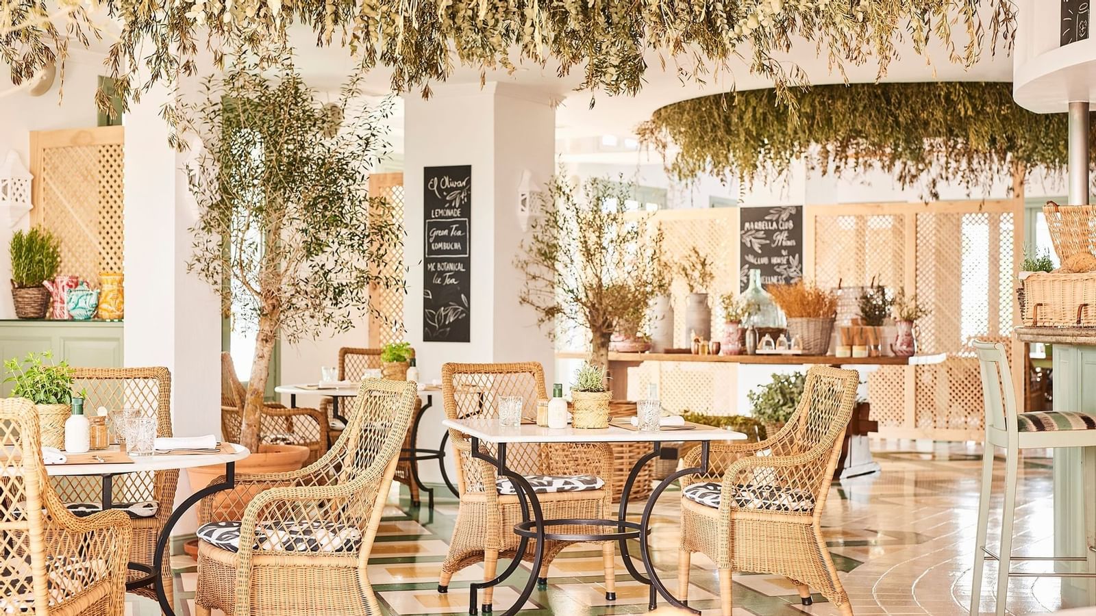 Wicker dining chairs and tables placed under a lush ceiling arrangement of dried hanging flowers at the Marbella Club