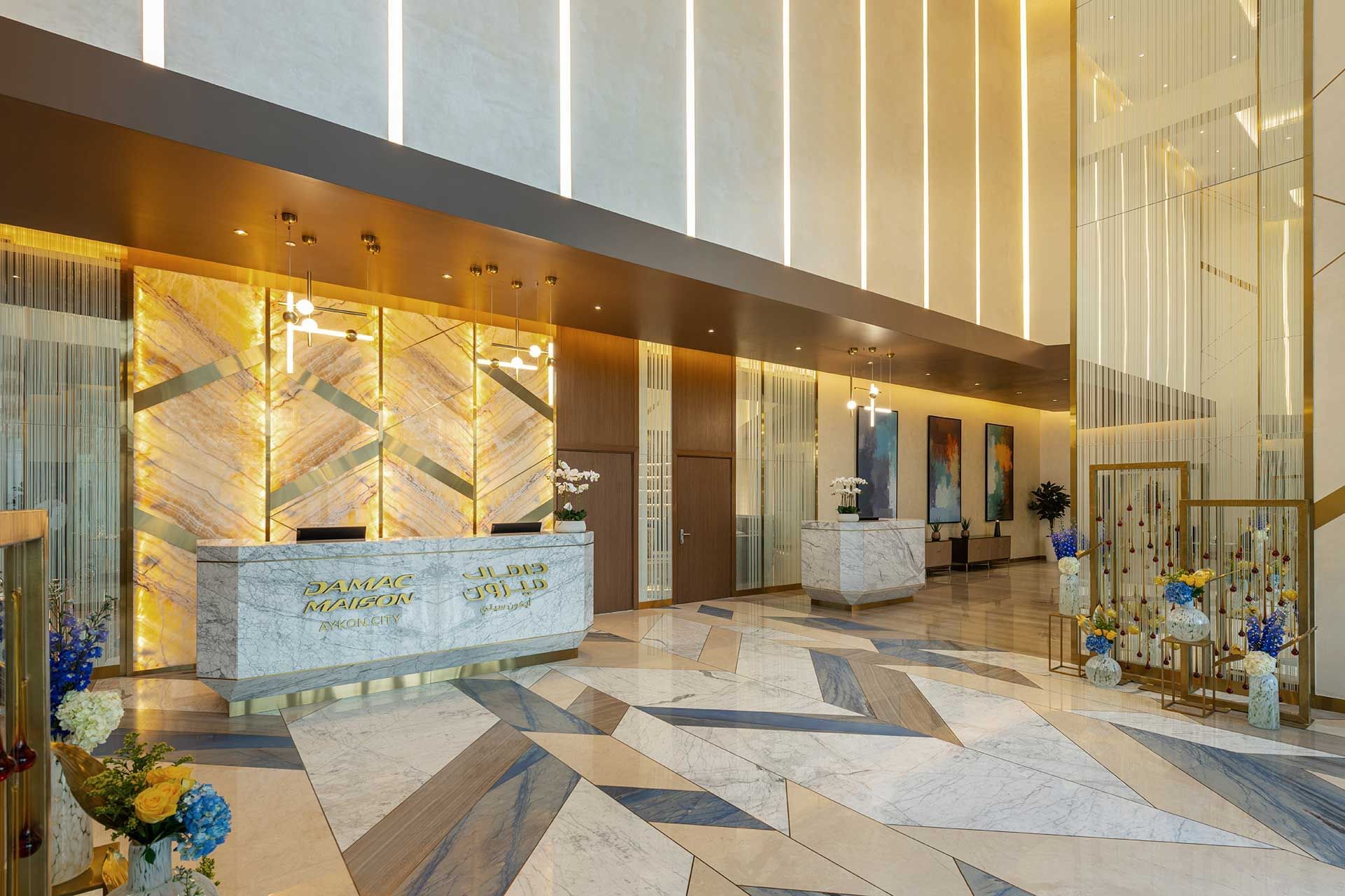 Lobby with marble reception desk, vertical light strips and elegant decor at DAMAC Maison AYKON City