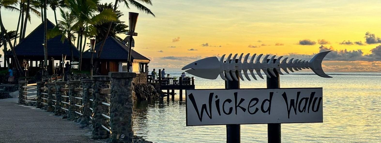 Wicked Walu sign by a stone path under palm trees surrounding a coastal lagoon in Wicked Walu at Warwick Fiji Resort and Spa