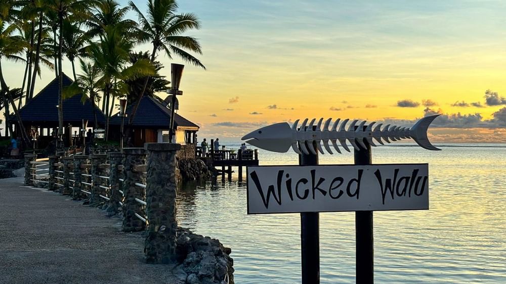 Wicked Walu sign by a stone path under palm trees surrounding a coastal lagoon in Wicked Walu at Warwick Fiji Resort and Spa