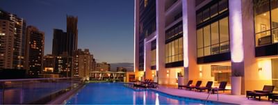 Float Bar rooftop pool with lounge chairs and glowing pillars, overlooking the night skyline at Megapolis Hotel Panama