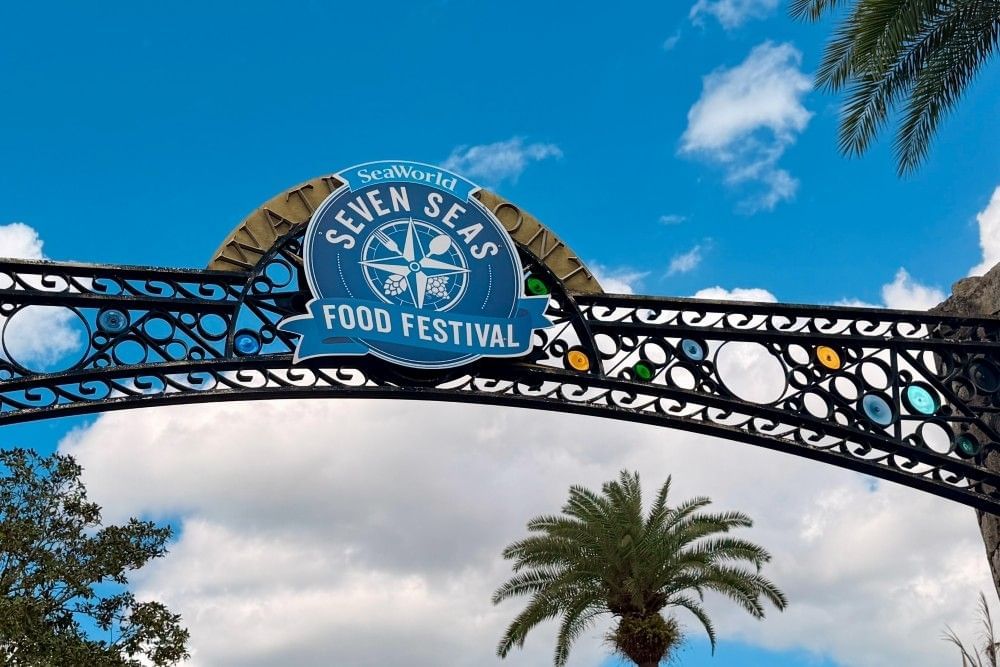 A close-up of an archway sign that reads SeaWorld Seven Seas Food Festival, arching through the sky.