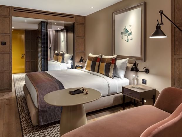 King Room featuring large bed with a chaise lounge and hanging wall art at The Londoner Hotel