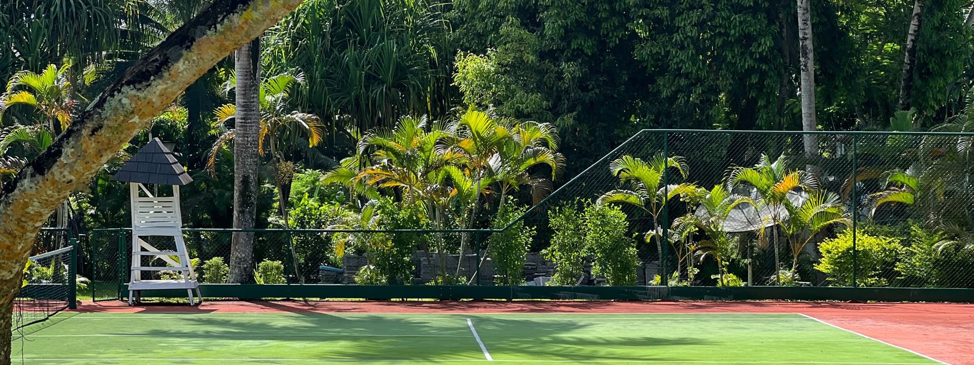Green and red tennis court surrounded by tropical plants at Warwick Fiji Resort and Spa in Korolevu