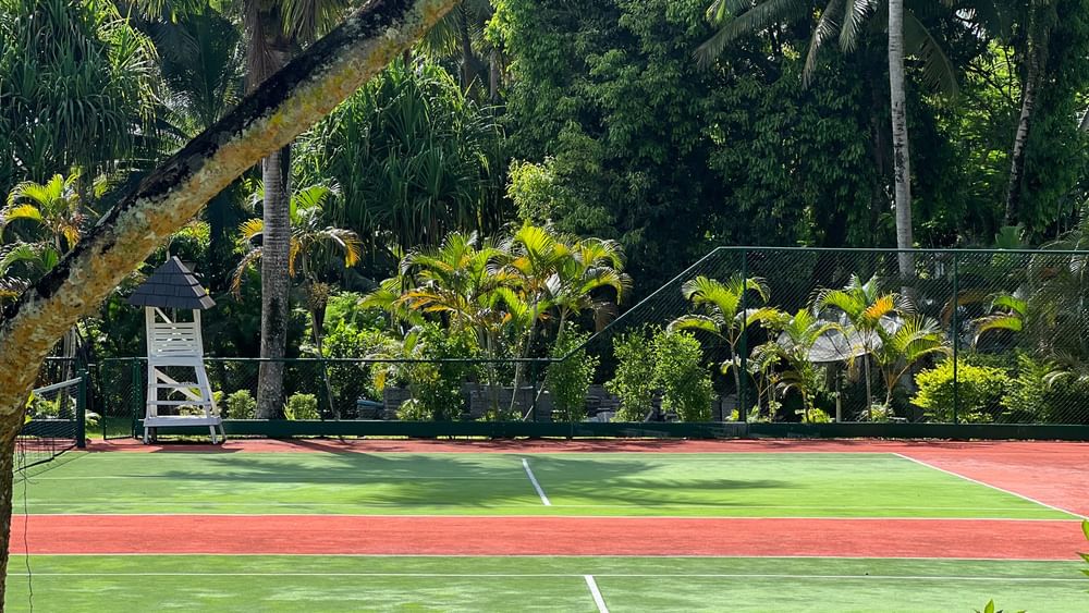 Green and red tennis court surrounded by tropical plants at Warwick Fiji Resort and Spa in Korolevu.