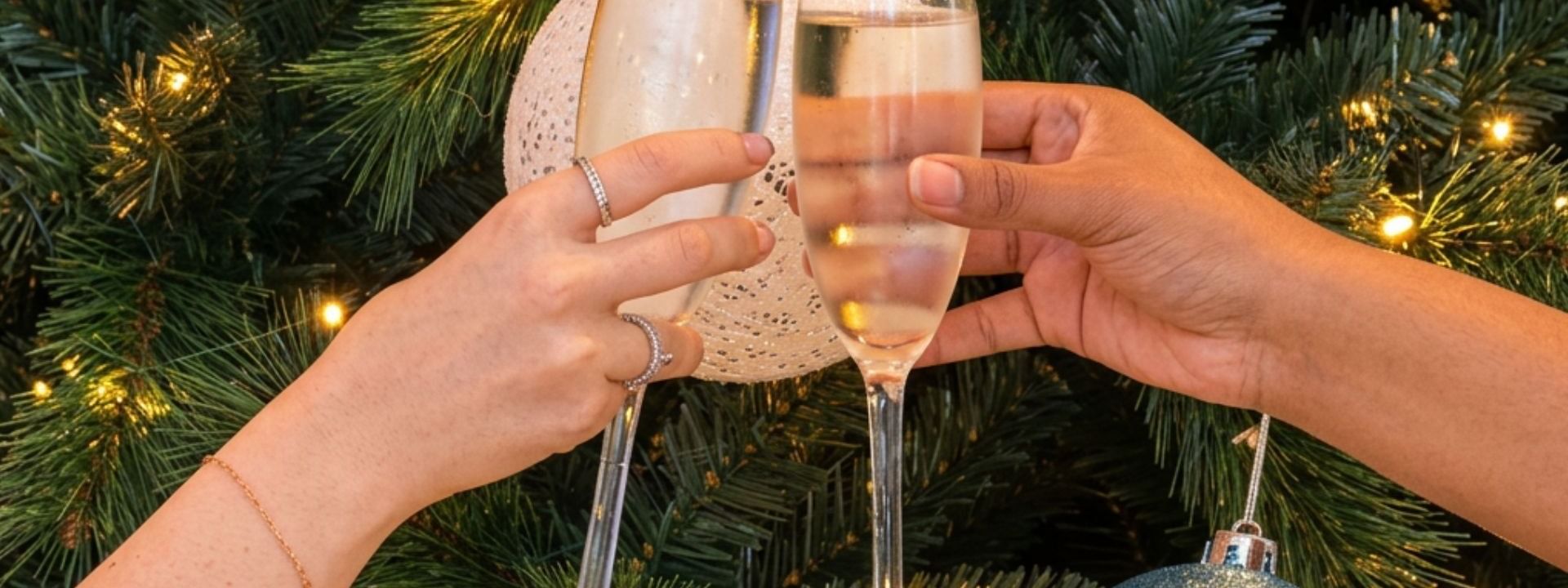 Two hands toasting champagne flutes in front of a decorated Christmas tree with twinkling lights and ornaments in novotel sydney darling square