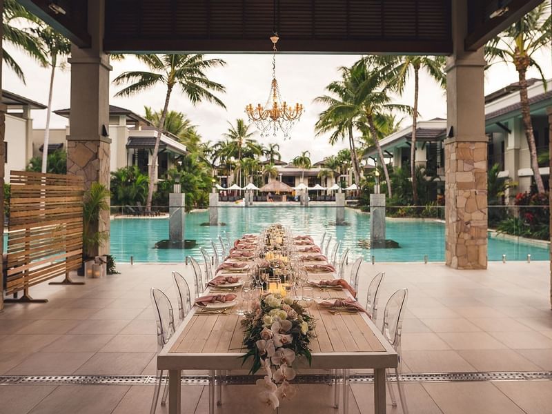 Outdoor wedding set up with long dining table by the pool at Pullman Port Douglas Sea Temple Resort & Spa