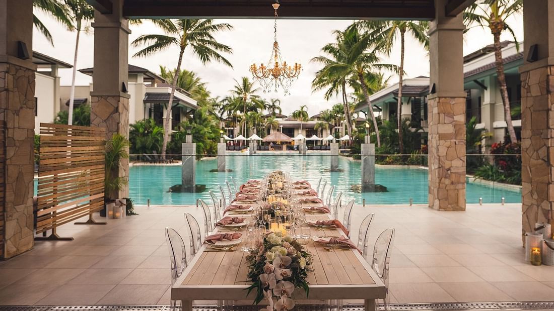Outdoor wedding set up with long dining table by the pool at Pullman Port Douglas Sea Temple Resort & Spa