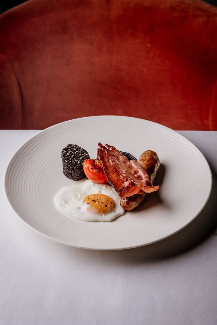 Full English breakfast placed by a red chair at The Capital Hotel, Apartments and Townhouse