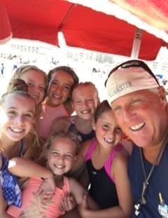 Surf instructor Jack takes a photo with kids after a surf lesson in Diamond Beach
