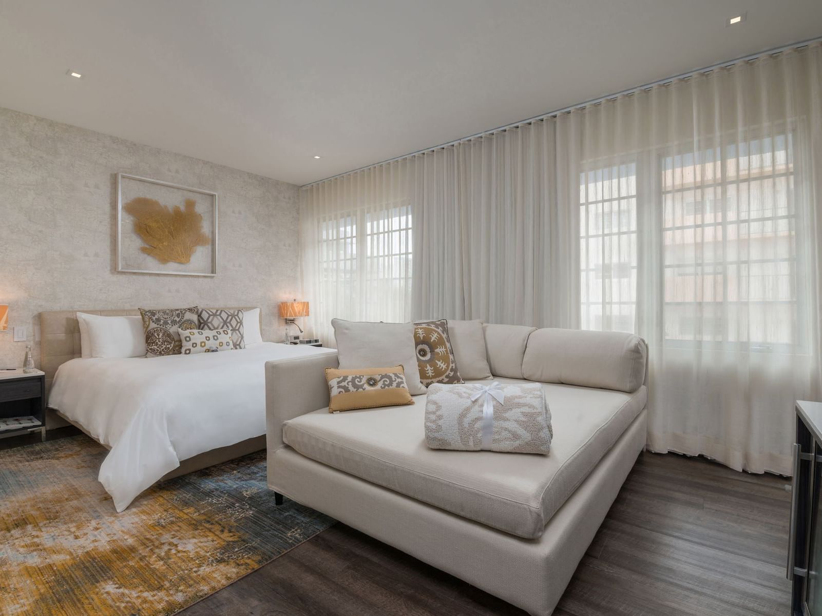 bed and couch in room with wooden floors