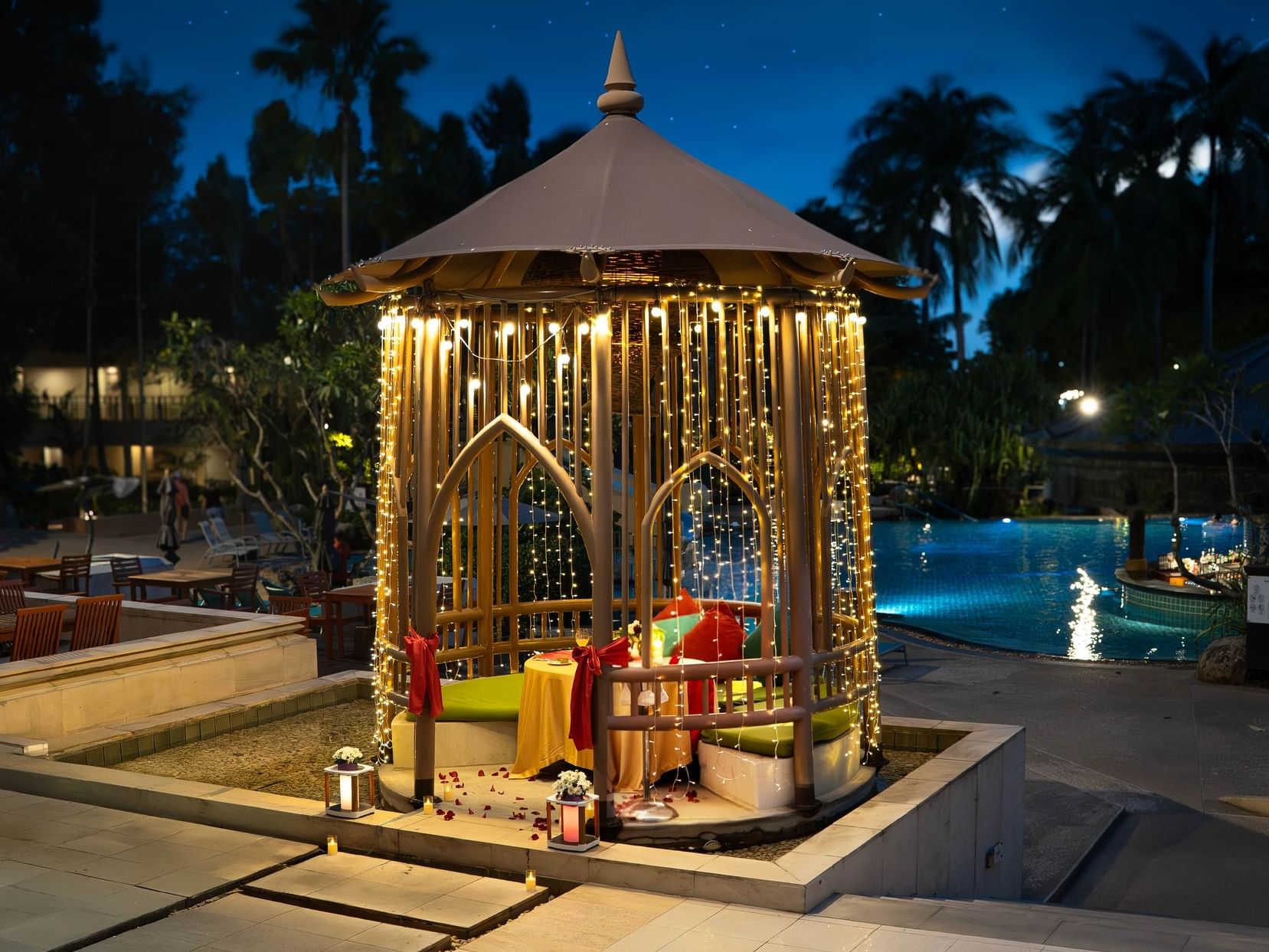Romantic private dinner setup by the pool with fairy lights at Paradox Resort Phuket, Karon Beach
