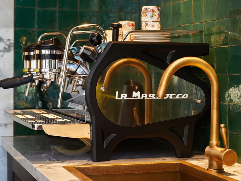 Stylish, modern espresso machine and brass faucet on a marble counter in Coffeebar at El Prado Hotel