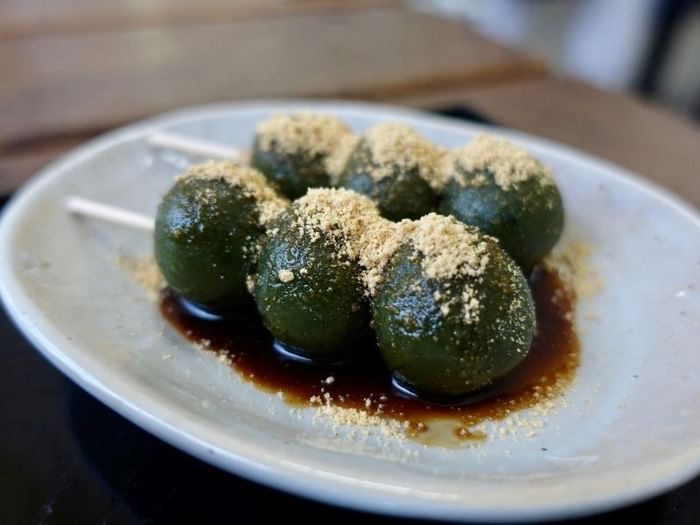 Five skewered green balls with sauce and topping on a white plate at Park Hotel Group