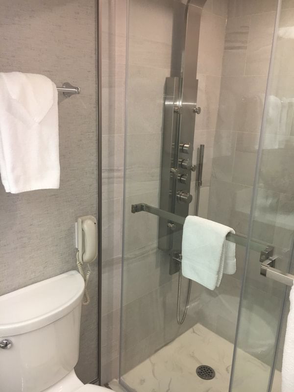 A bathroom with a shower & towels at Cartier Place Suite Hotel
