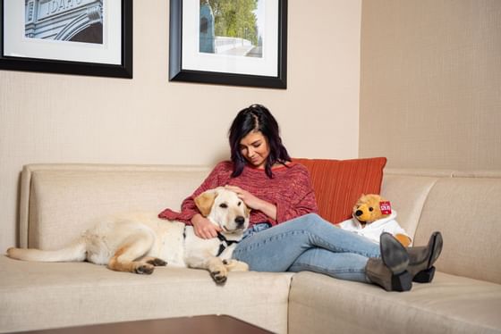 Women sitting on a sofa & petting a dog at Hotel 43